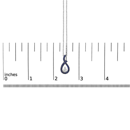 White metal necklace with a loop-shaped pendant featuring a central pear-shaped white gemstone surrounded by round blue gemstones, shown on a scale from a front angle.
