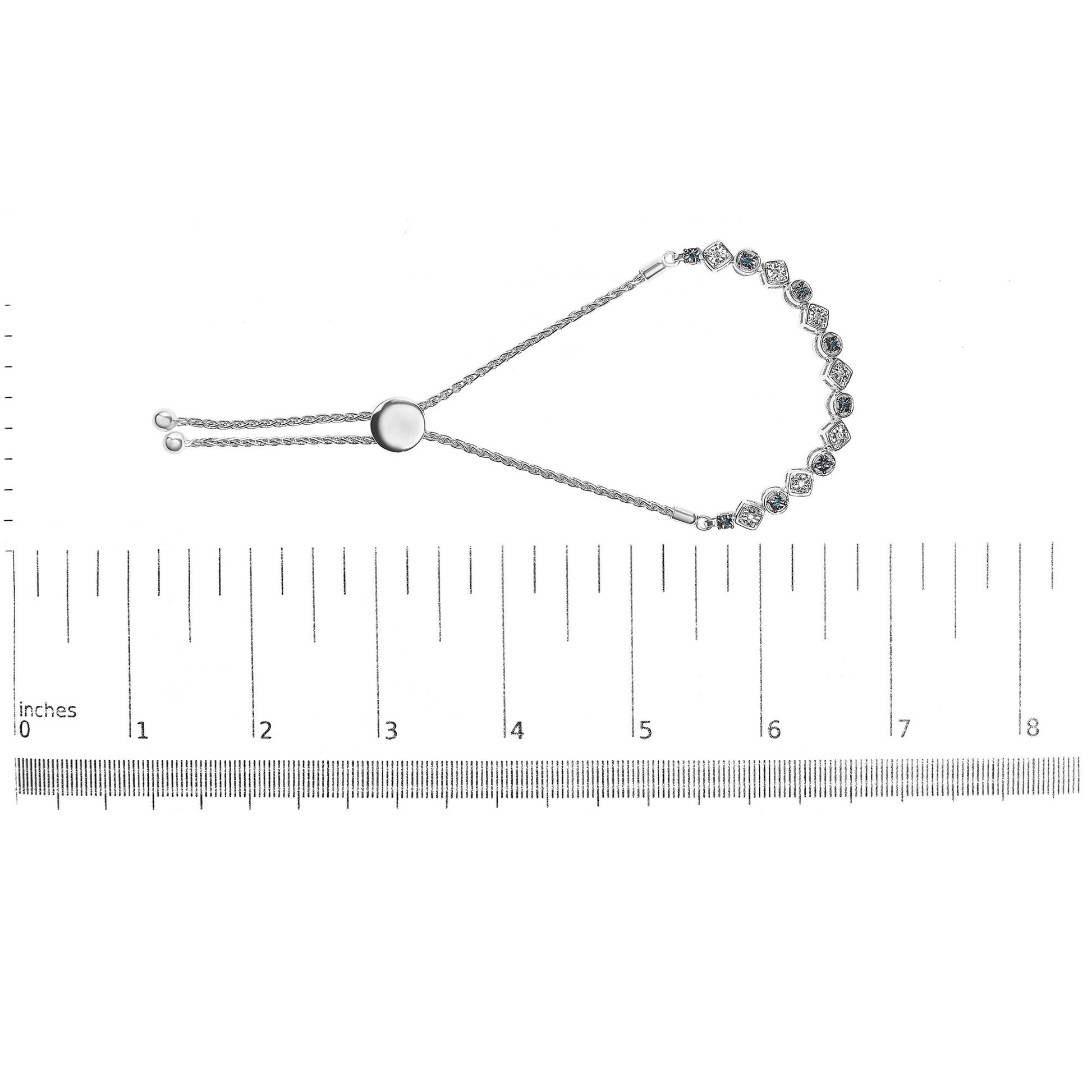 White metal bracelet with alternating white and blue round gemstones in miracle settings, shown from above on a ruler for size reference.