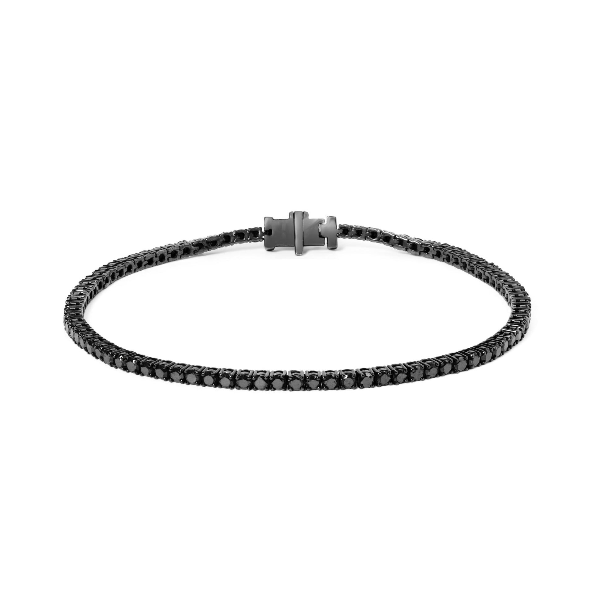 Close-up front angle of a white metal bracelet with round black gemstones set in four-prong and shared prong settings, laid flat with clasp visible.