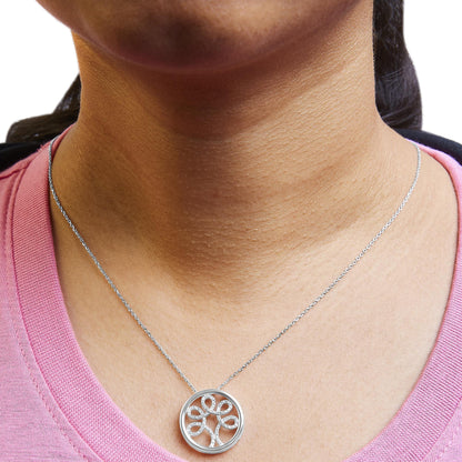 Close-up front view of a white necklace with a circular pendant featuring an intricate looped design adorned with white round gemstones, worn on a model with a pink top.