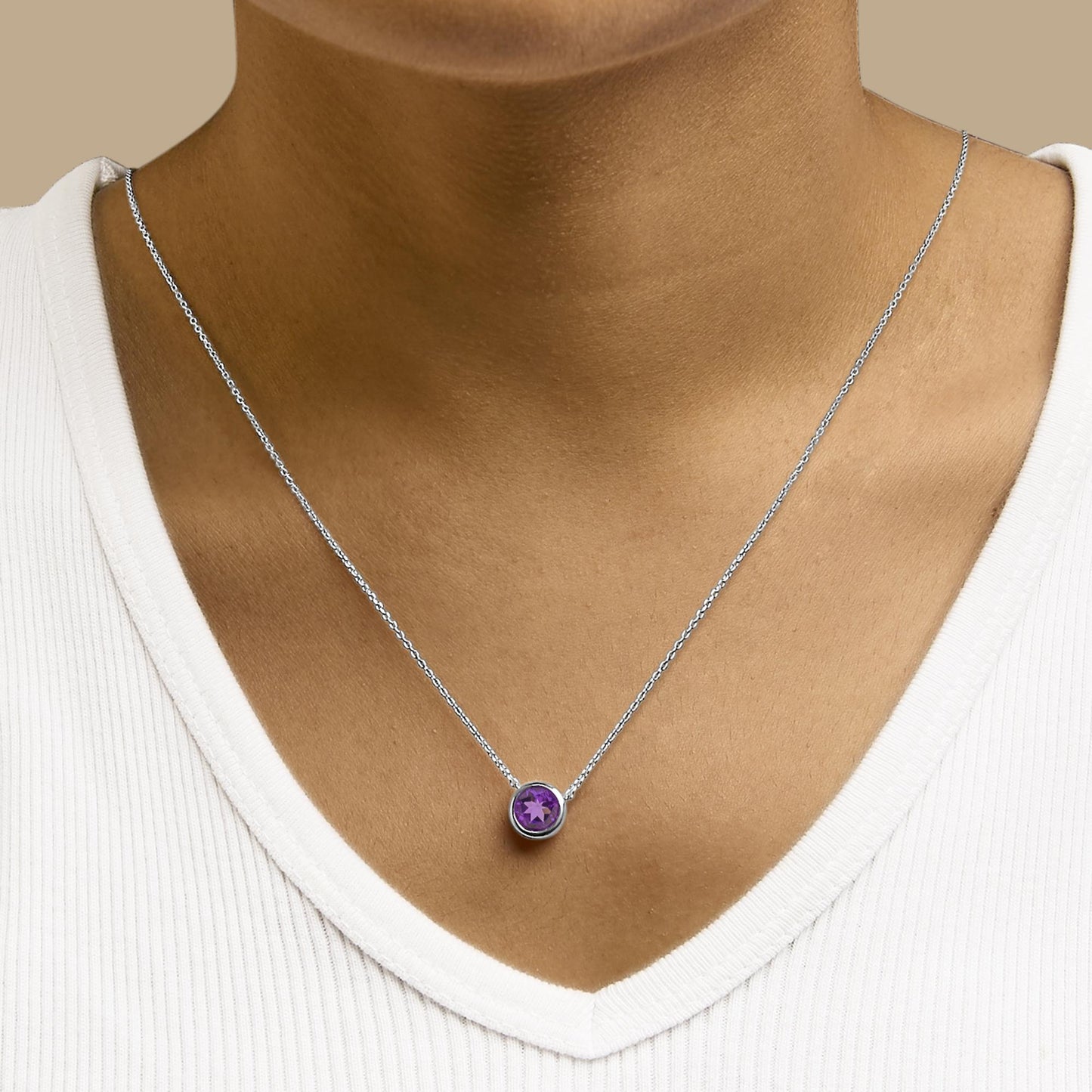 White necklace with a round purple gemstone in a bezel setting, shown worn on a model in a close-up front view.