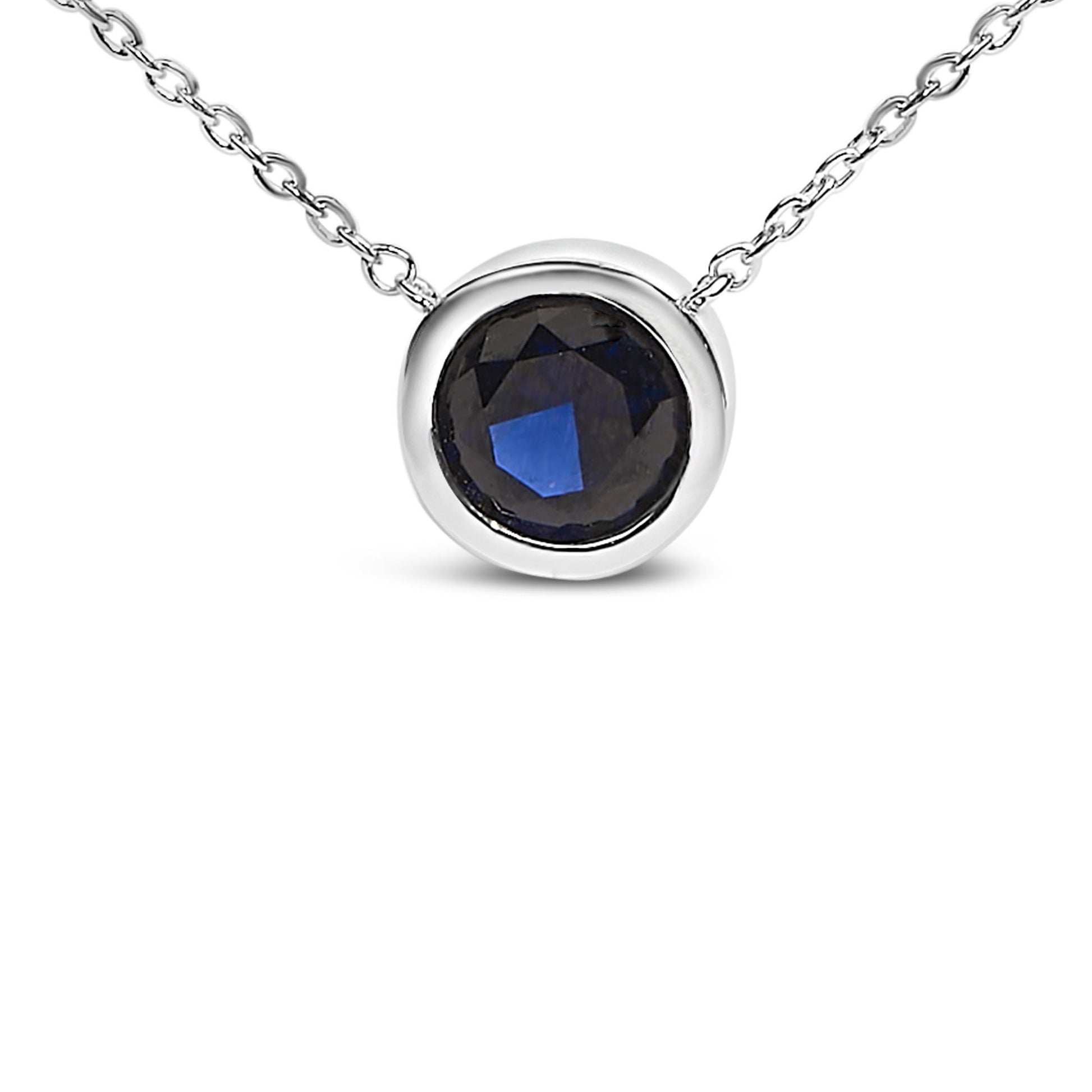 Close-up front angle of a white metal necklace with a round blue gemstone in a bezel setting.