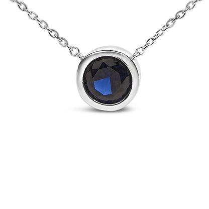 Close-up front angle of a white metal necklace with a round blue gemstone in a bezel setting.