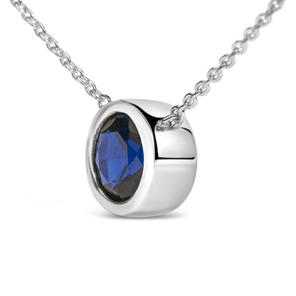 Close-up front angle of a white metal necklace with a round blue gemstone in a bezel setting.