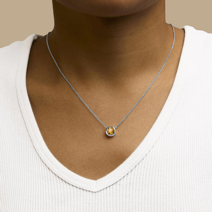 White necklace with a round yellow gemstone in bezel setting, shown worn on a model, front view.