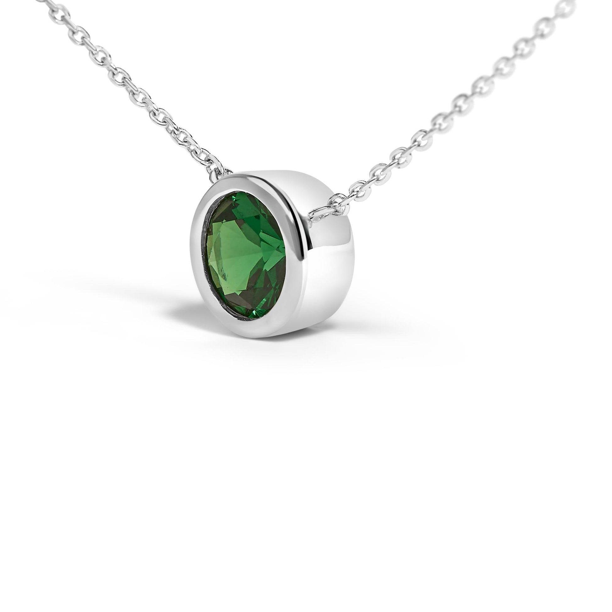Close-up front angle of a white metal necklace featuring a round green gemstone in a bezel setting.