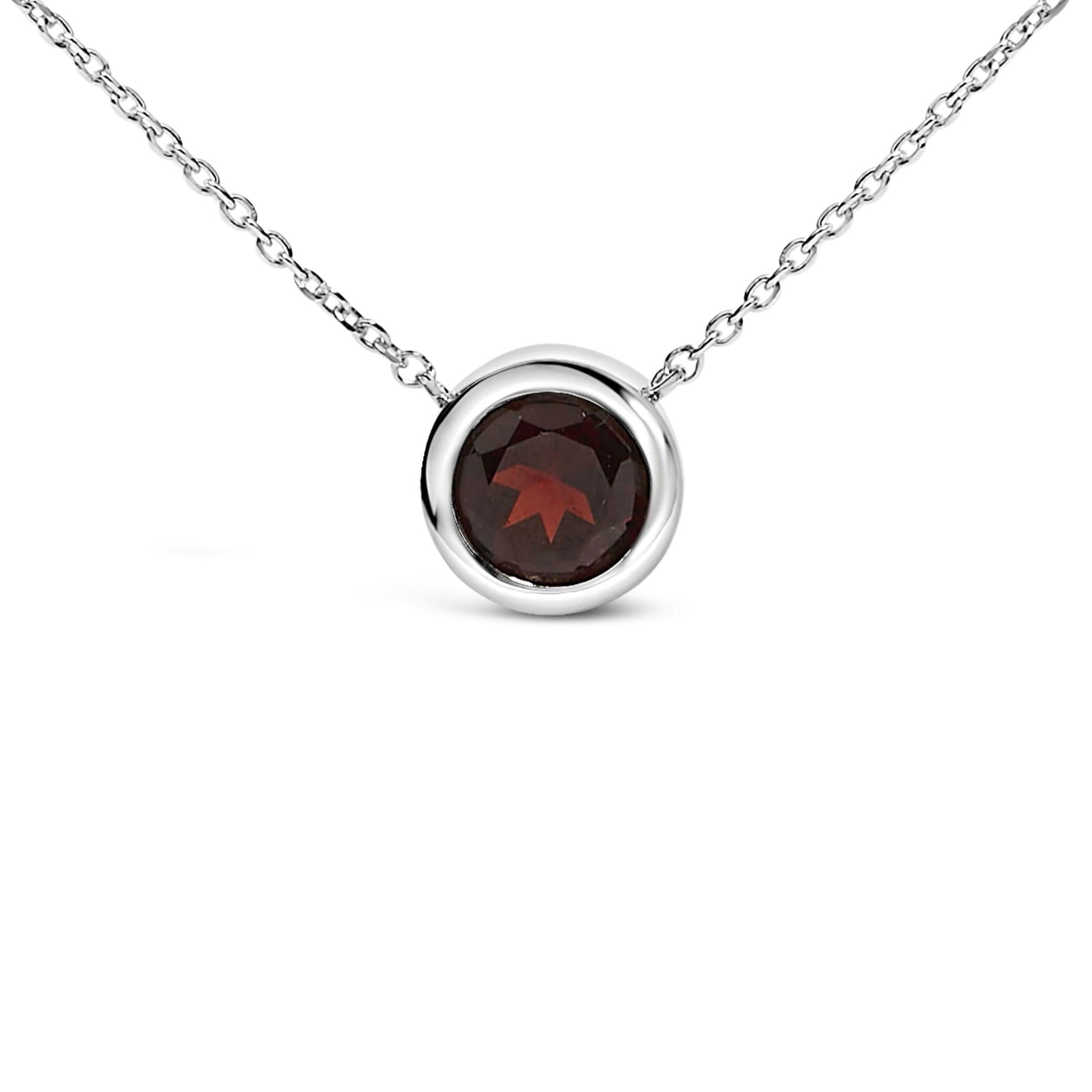 Close-up front angle of a white metal necklace with a round red gemstone in a bezel setting.