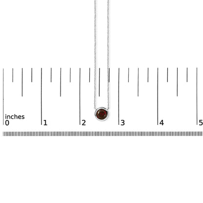 White necklace with round red gemstone in bezel setting shown on a ruler scale, front view.