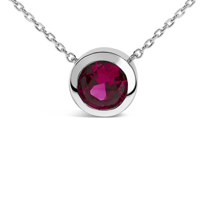 Close-up front view of a white metal necklace with a round red gemstone in a bezel setting.