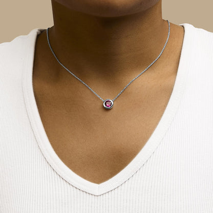 White necklace with a round red gemstone in bezel setting, shown worn on a model from a front angle.