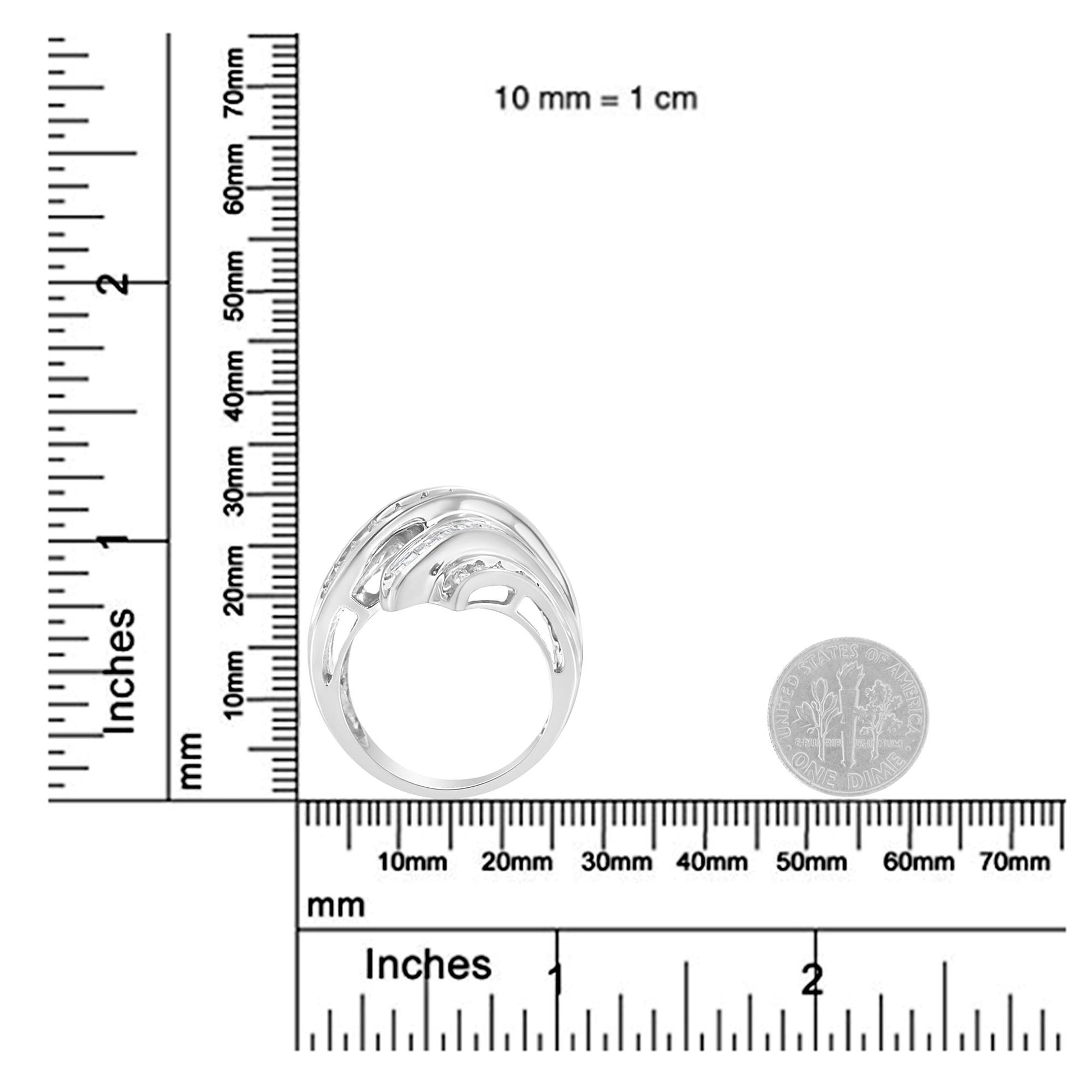 White metal ring with channel-set round and baguette white gemstones in a swirling design, shown in a side view on a ruler and next to a coin for size reference.