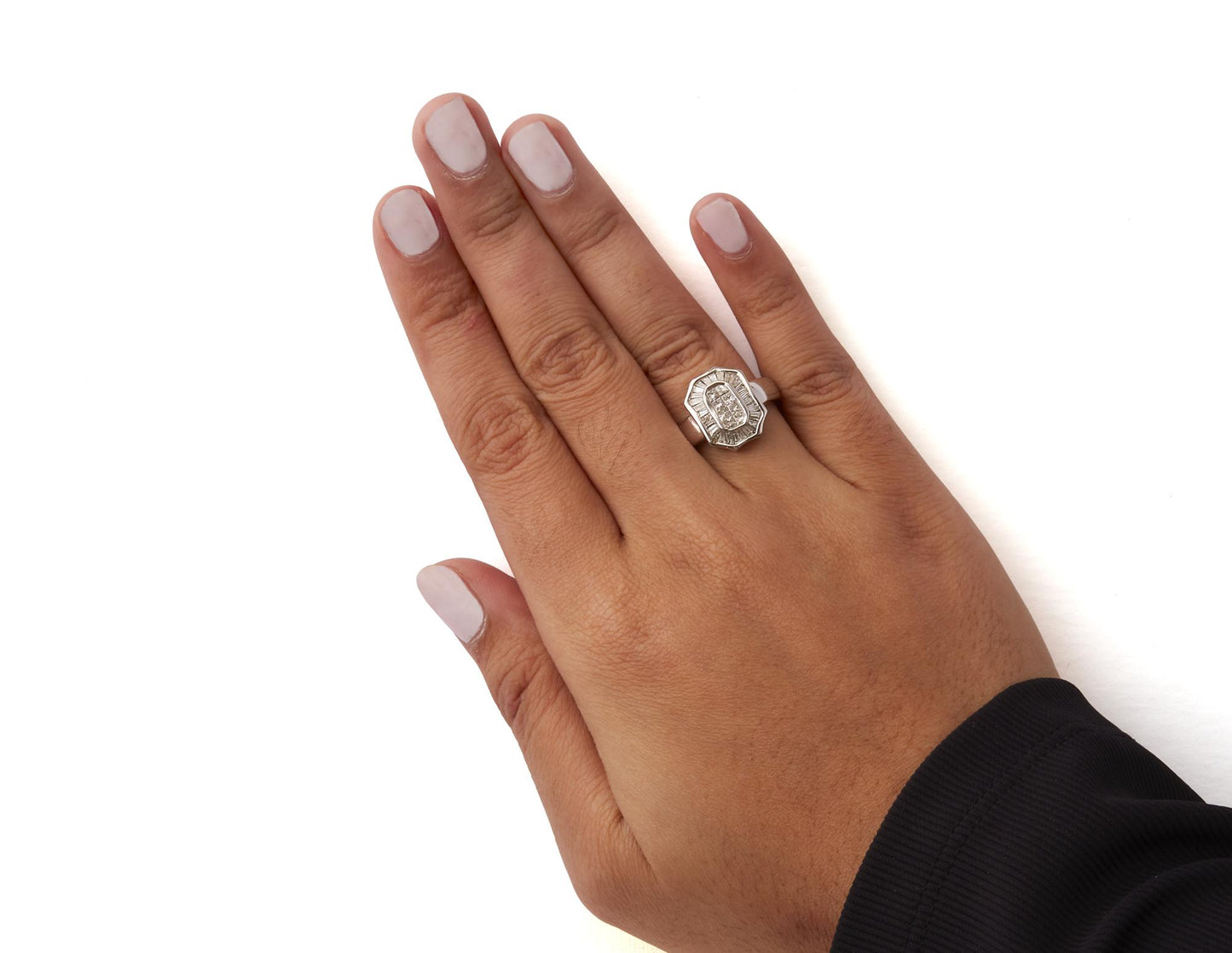 Close-up top view of a hand wearing a white metal ring featuring white baguette-shaped gemstones in a channel setting and white princess-shaped gemstones in an invisible setting.