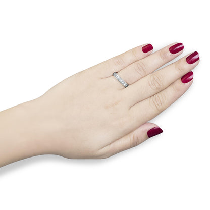 White metal ring with a channel setting of round white gemstones on a model’s hand, top-down angle.