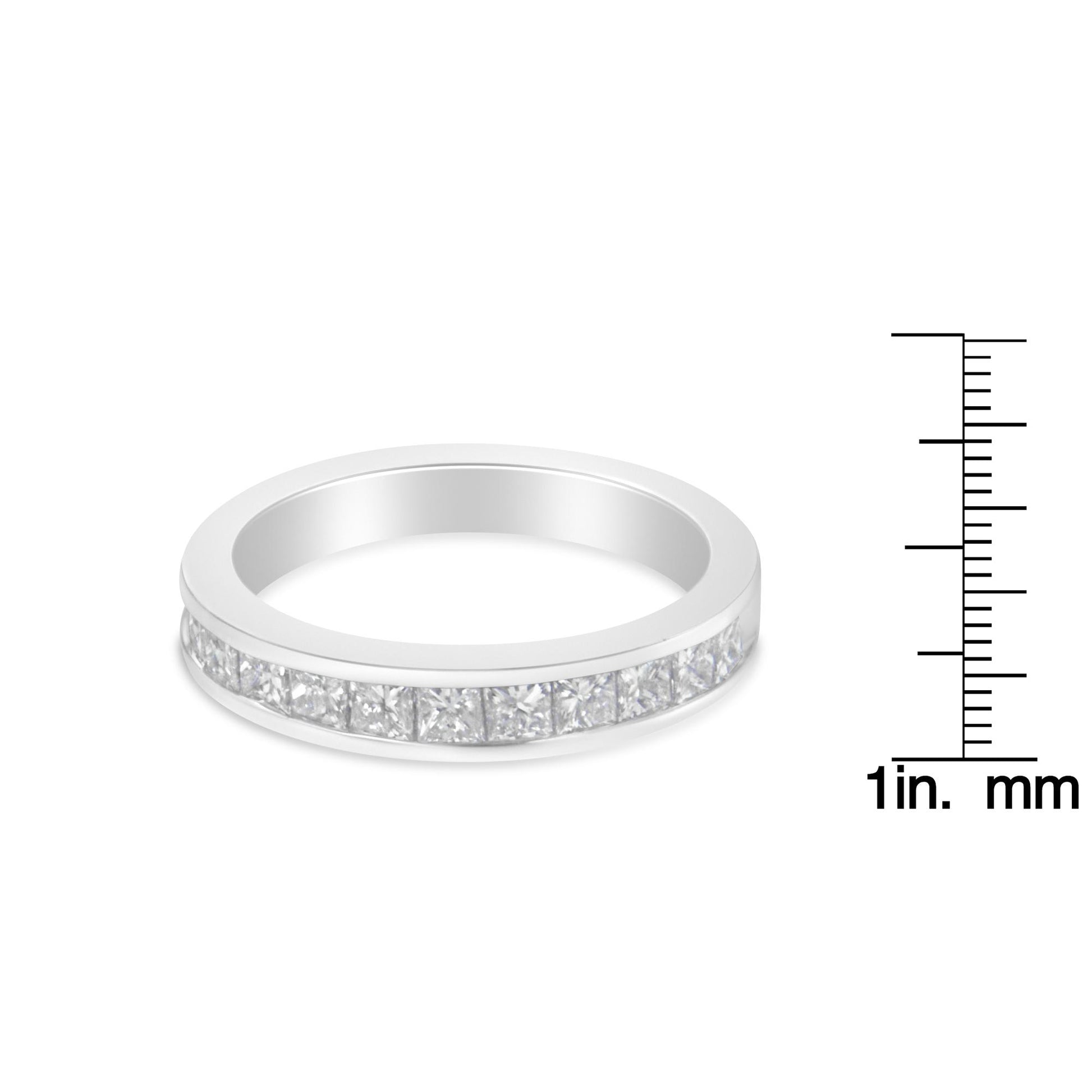 White metal ring with channel-set princess-shaped white gemstones viewed from a slight side angle, shown next to a ruler for size reference.