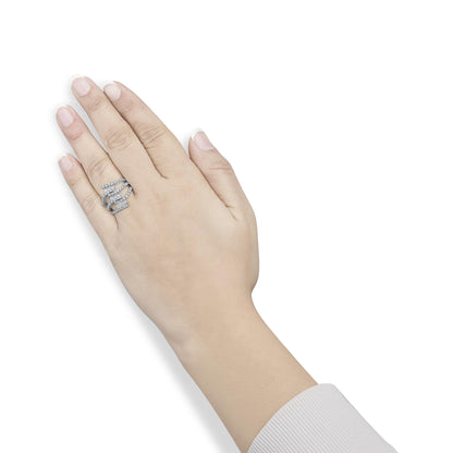 White metal ring with multiple bands featuring round white gemstones in prong settings and baguette white gemstones in channel settings, shown worn on a model's left hand from a top angle.