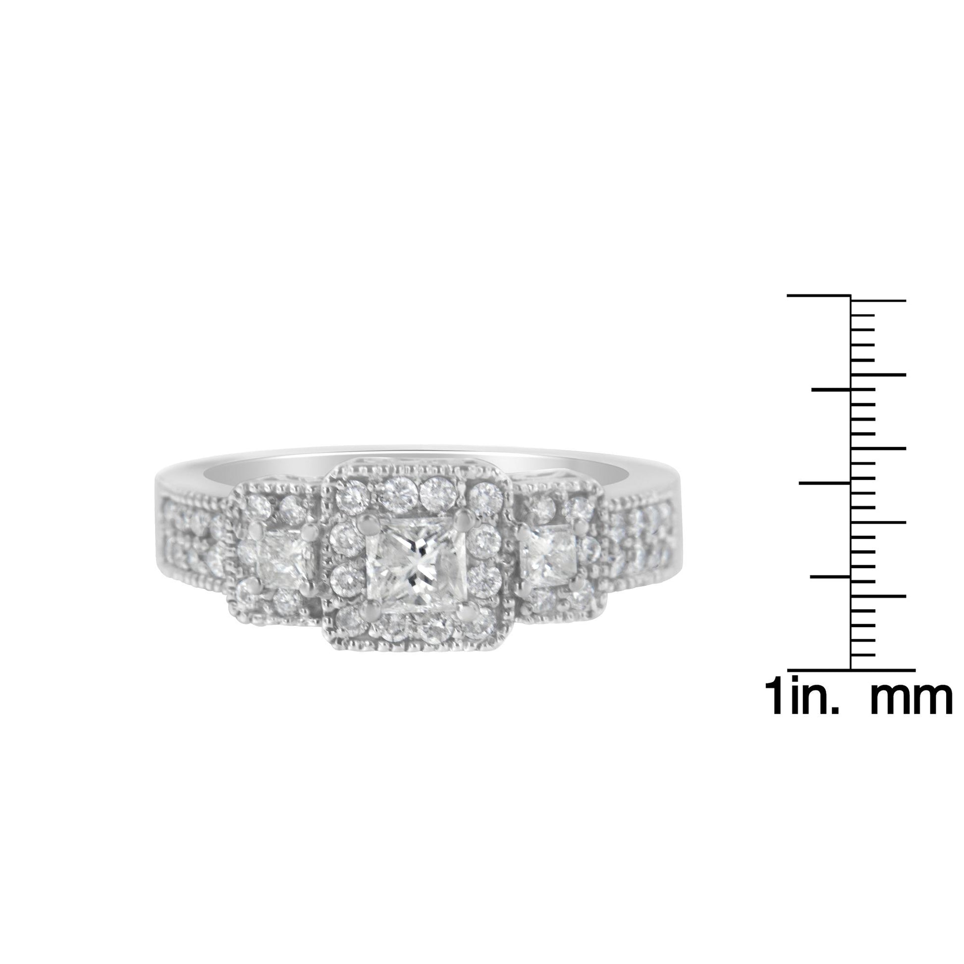 Front view of a white metal ring with three princess shape white gemstones in prong settings, surrounded by multiple small round white gemstones in prong settings, shown next to a ruler for size reference.