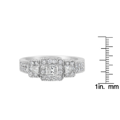 Front view of a white metal ring with three princess shape white gemstones in prong settings, surrounded by multiple small round white gemstones in prong settings, shown next to a ruler for size reference.