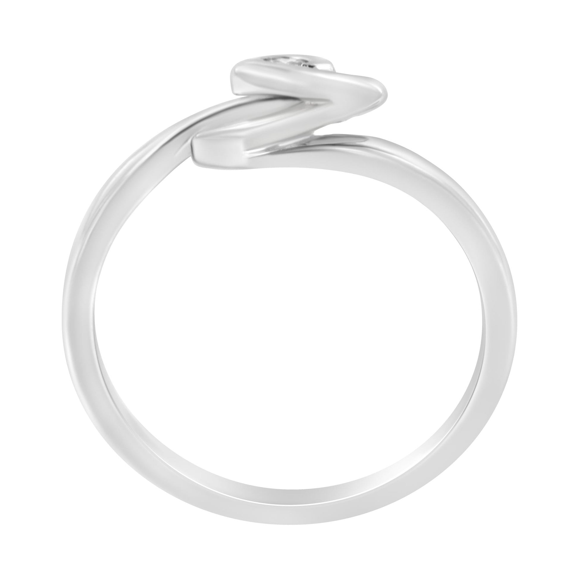 White metal ring viewed from the side with a round white gemstone in bezel setting and a zigzag design.