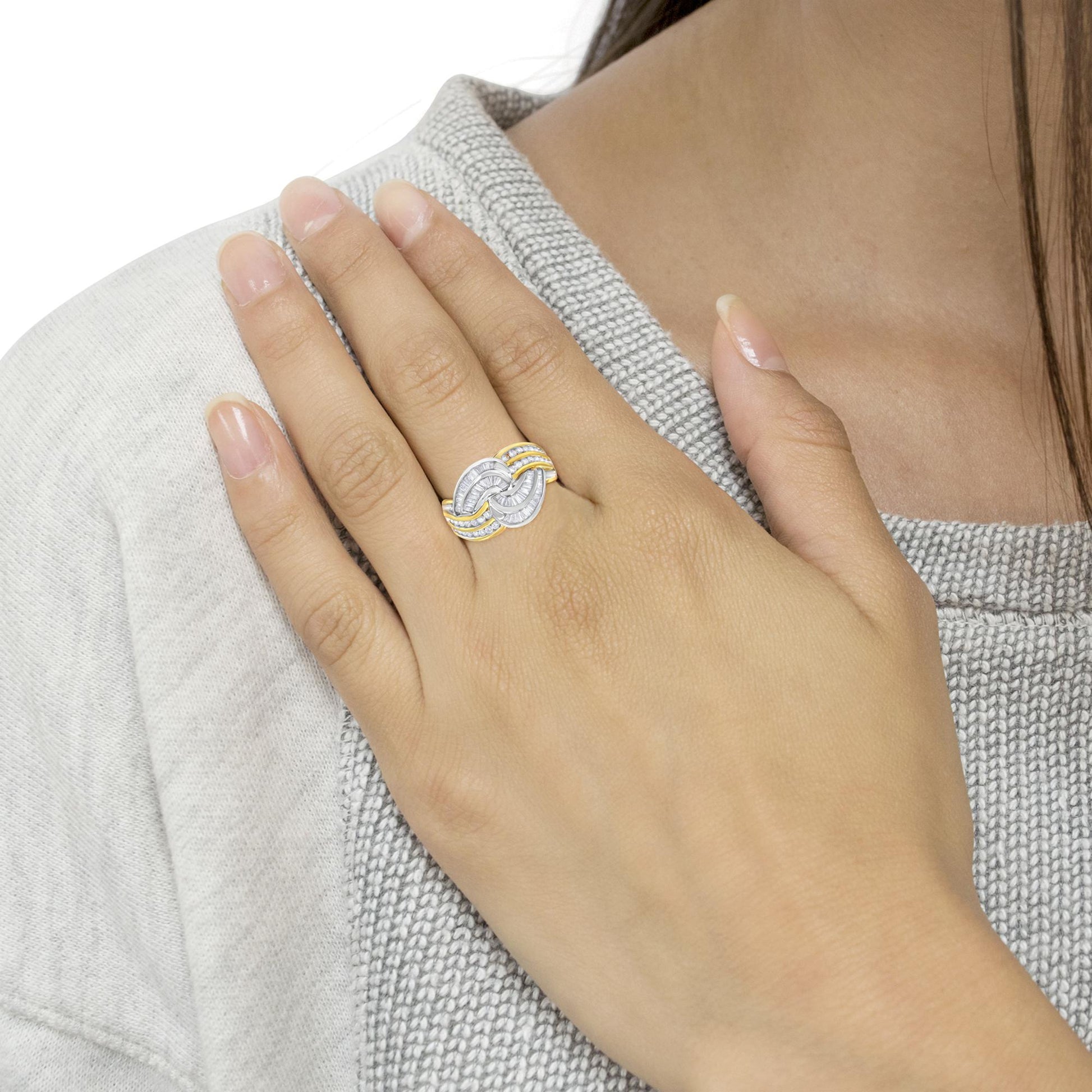 Close-up front angle of a two-tone ring on a model's finger, featuring white round and baguette shaped gemstones in channel settings.
