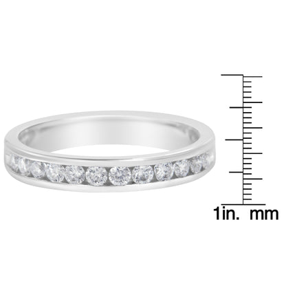 Close-up front view of a white metal ring with round white gemstones in a channel setting, shown next to a ruler for size reference.