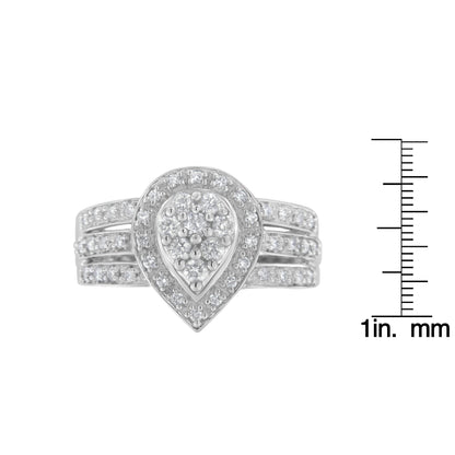 Front view of a white metal ring with a teardrop-shaped cluster of round white gemstones in pave setting, displayed next to a scale for size reference.