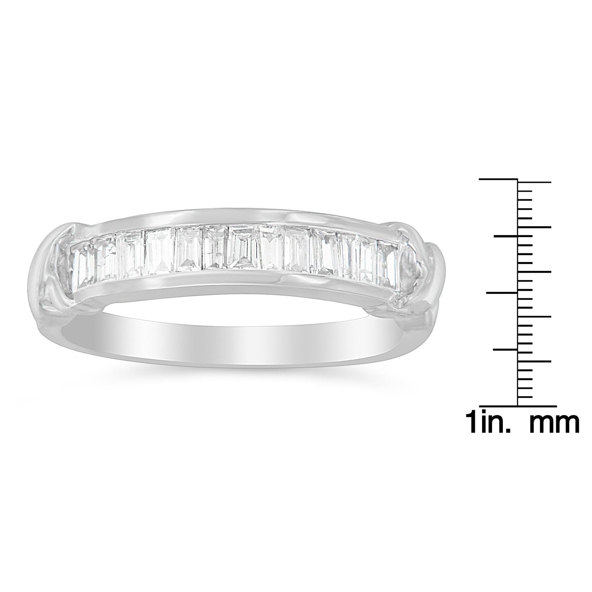 White metal ring with a row of baguette-shaped white gemstones in a channel setting, shown from a side angle, placed next to a ruler for size reference.