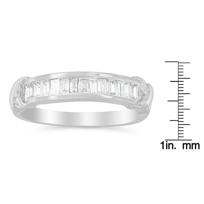 White metal ring with a row of baguette-shaped white gemstones in a channel setting, shown from a side angle, placed next to a ruler for size reference.