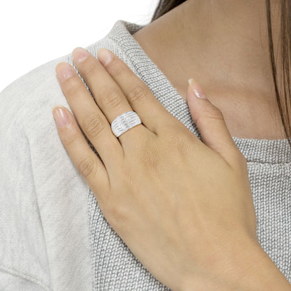 Close-up of a white metal ring with multiple rows of baguette-shaped white gemstones in a channel setting, worn on a model's finger, angled slightly from above.