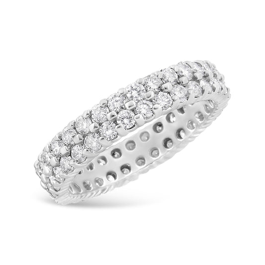 White metal ring with three rows of round white gemstones in prong settings, shown at a slight angle on a white background.