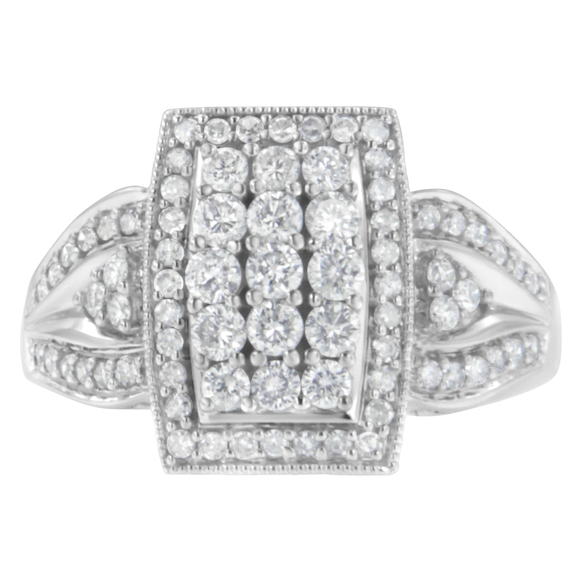 Top-down close-up of a white ring with a rectangular cluster of round white gemstones in a pave setting and additional gemstones on the band.