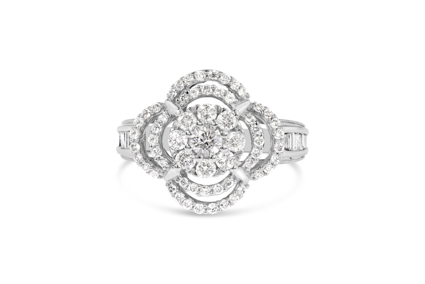 Front angle view of a white ring featuring a central round gemstone surrounded by layers of small round gemstones in prong settings and baguette gemstones in channel settings on the band.