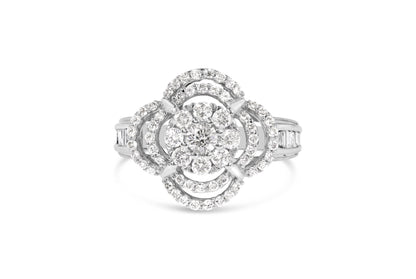 Front angle view of a white ring featuring a central round gemstone surrounded by layers of small round gemstones in prong settings and baguette gemstones in channel settings on the band.