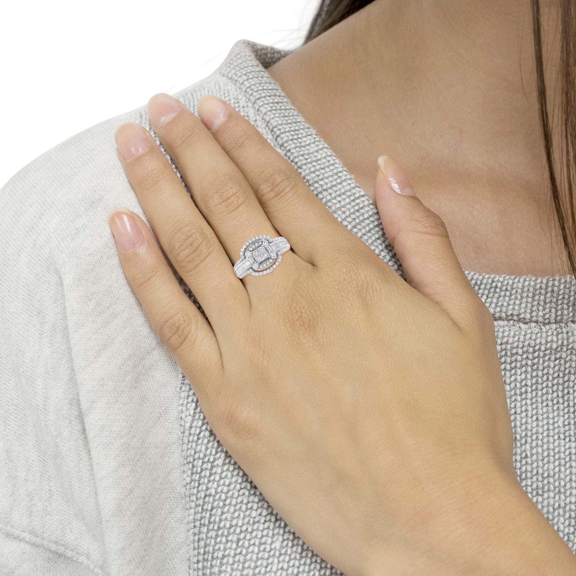 White metal ring with round, baguette, and princess shaped white gemstones in pave, channel, and invisible settings, worn on a model's finger, front angle view.