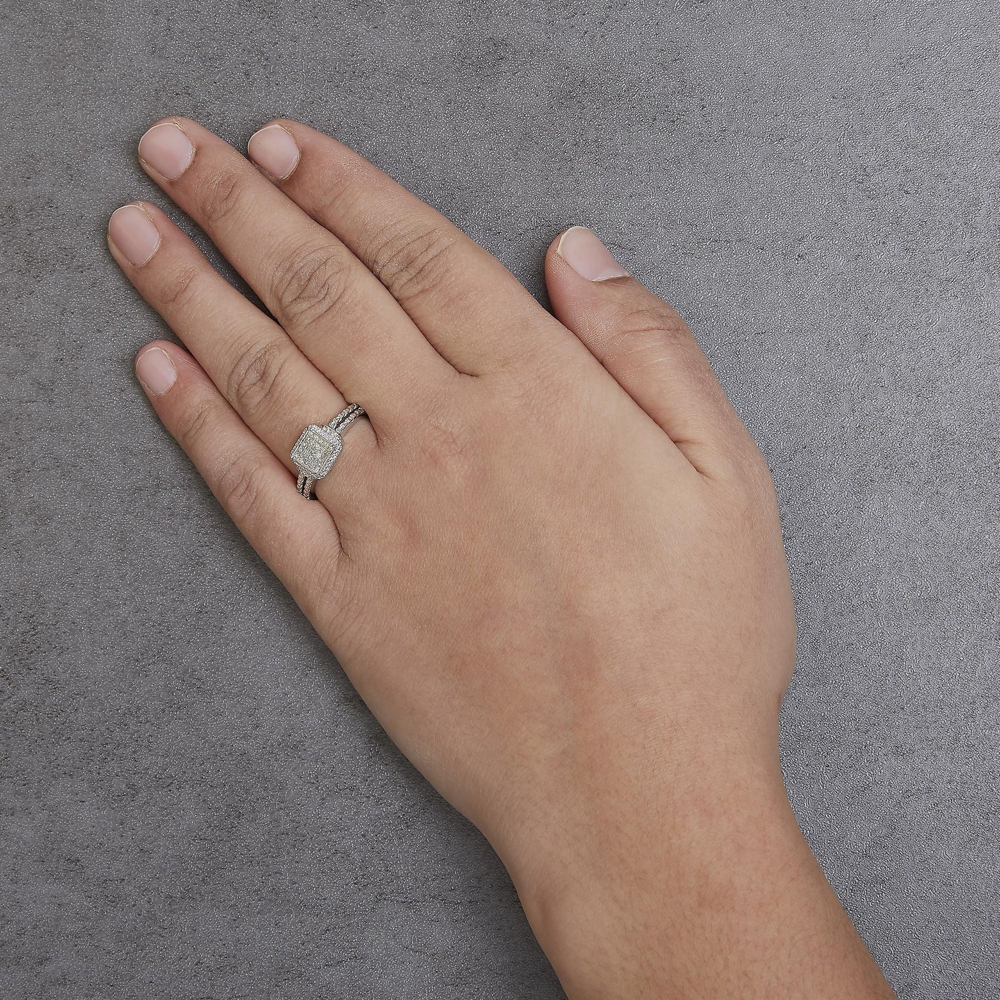 White metal ring with a princess-shaped cluster of white gemstones in an invisible setting, worn on a model's hand, shot from above at an angle.