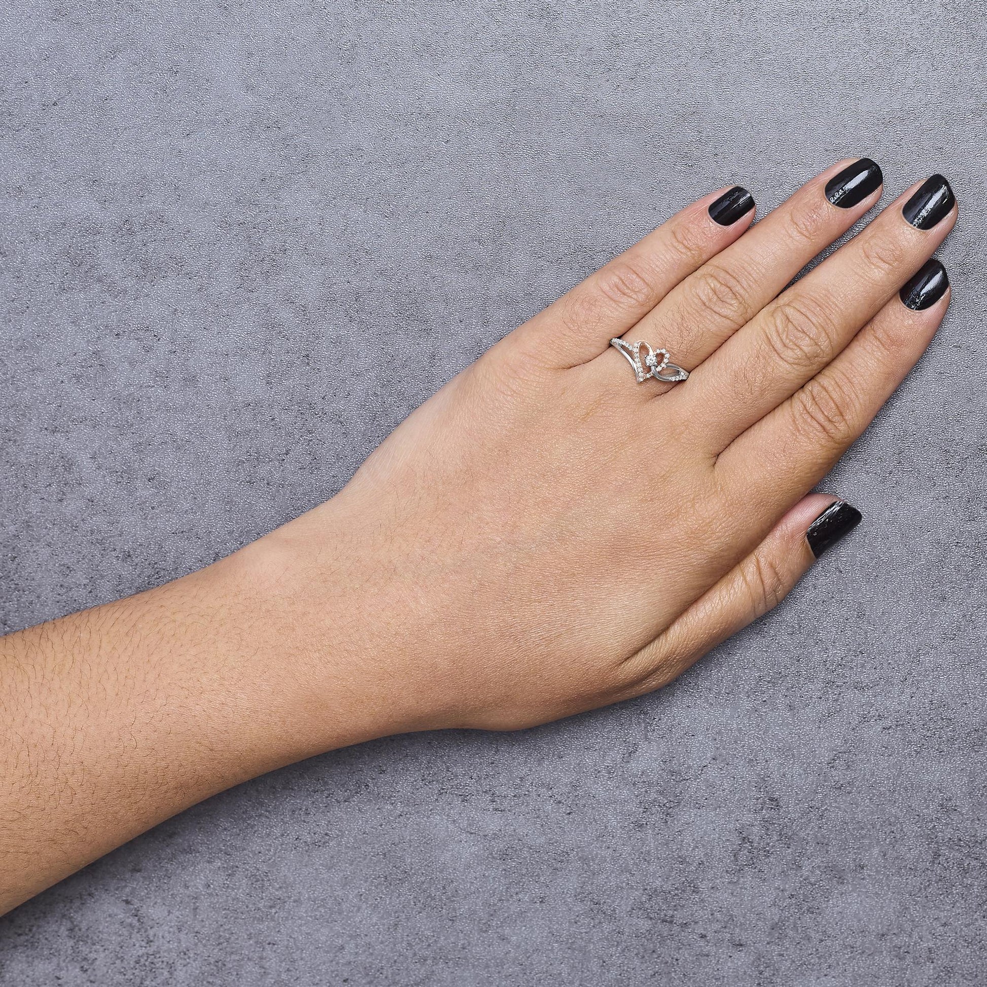 Hand wearing a white and rose metal ring with round white gemstones in prong settings, shown from above.