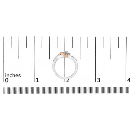 Top-down view of a white and rose metal ring with round prong-set white gemstones, placed on a ruler for size reference.