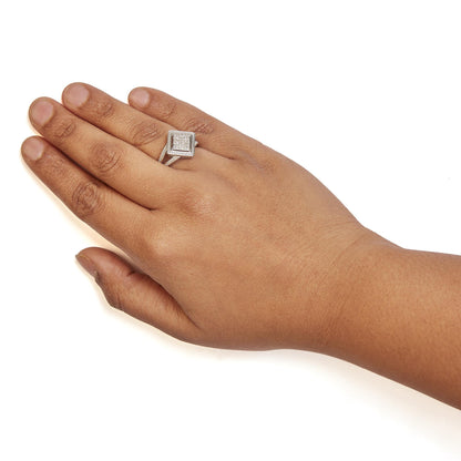 Close-up angled shot of a white metal ring with a square top featuring multiple small white gemstones in invisible setting, worn on a model's hand.