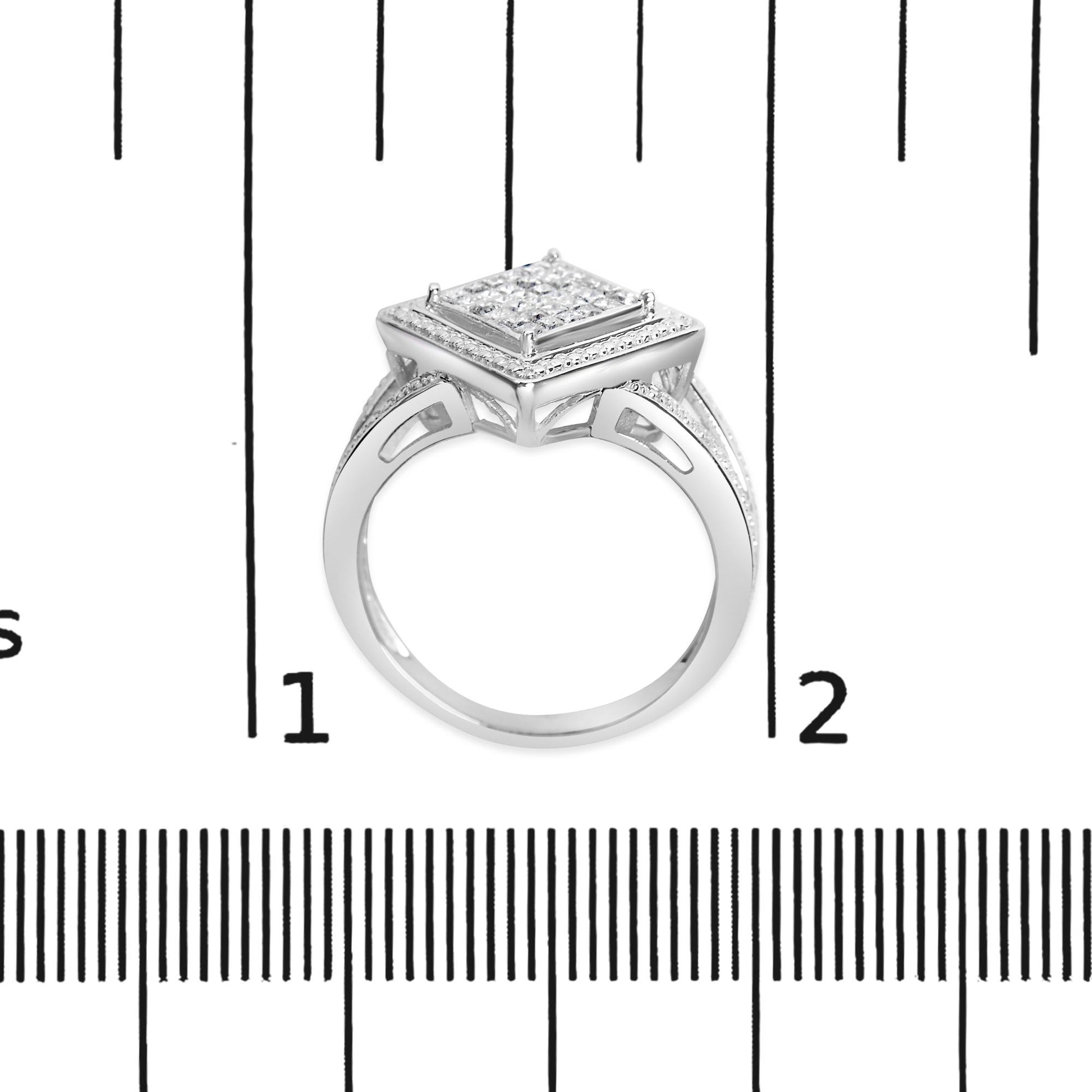 White metal ring with a square cluster of princess-shaped white gemstones in an invisible setting, shown from the side on a ruler for size reference.