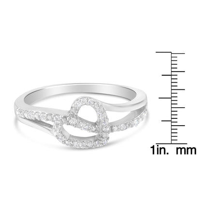 White metal ring with intertwined loop design adorned with round white gemstones in prong settings, shown at a slight angle next to a ruler for size reference.