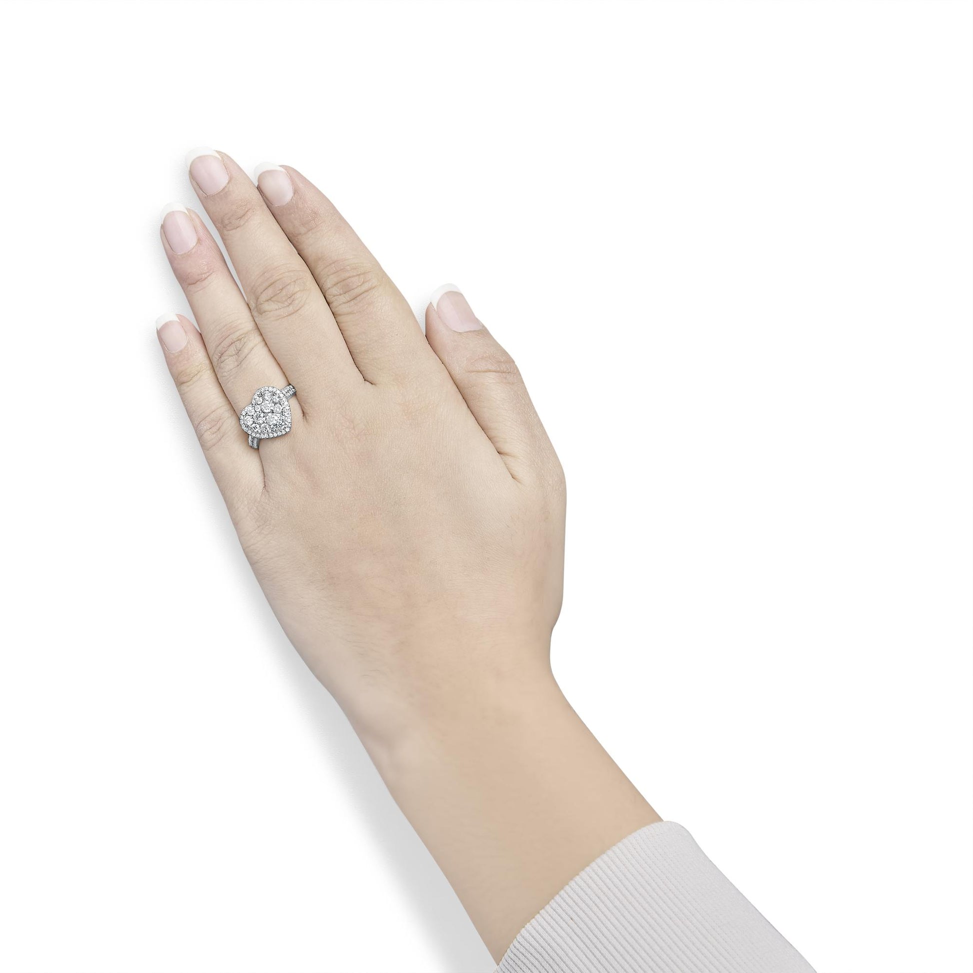 Close-up angle of a yellow metal ring with a heart-shaped cluster of white round gemstones, worn on a model's finger.