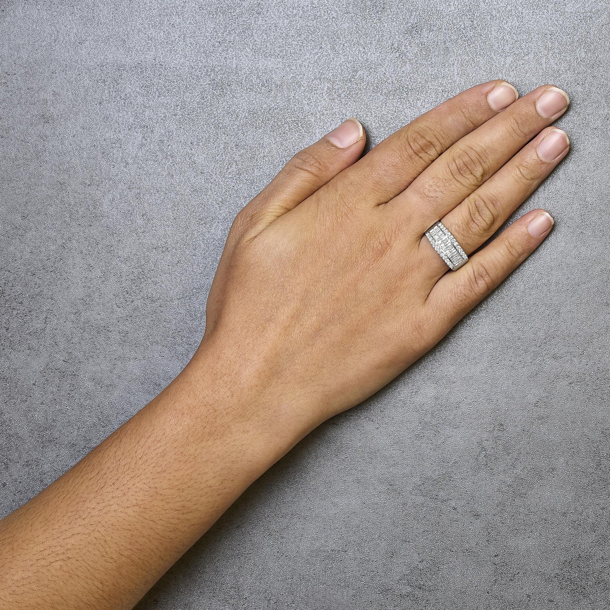 White metal ring with rows of round prong-set white gemstones between two rows of baguette channel-set white gemstones, shown on a model's hand from above.