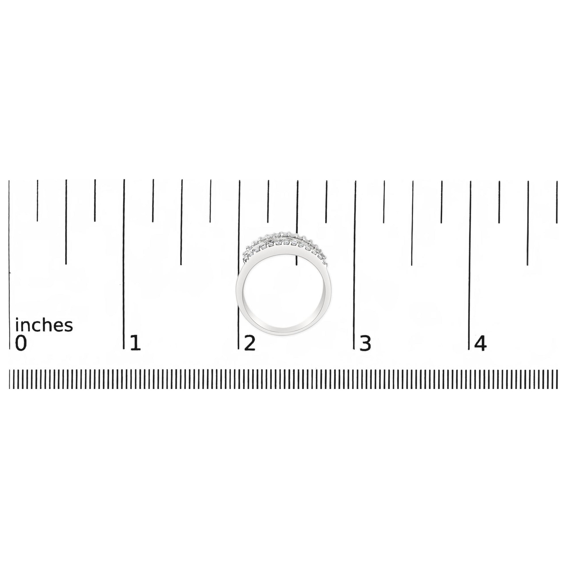 Top-down view of a white ring with round white gemstones in prong settings and baguette white gemstones in channel settings, placed on a ruler for size reference.