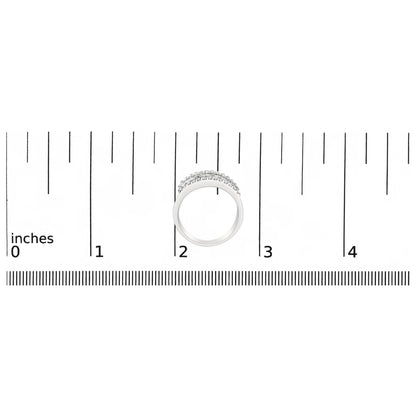 Top-down view of a white ring with round white gemstones in prong settings and baguette white gemstones in channel settings, placed on a ruler for size reference.