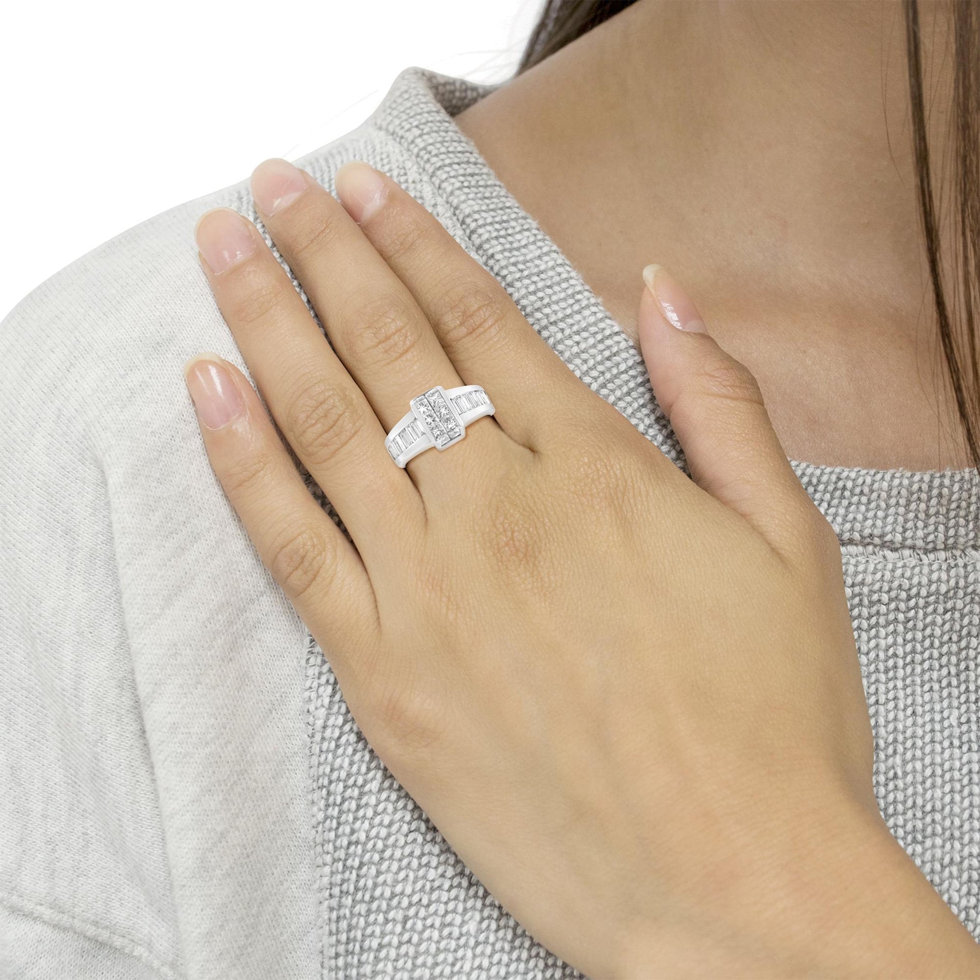 White metal ring with baguette and princess shape white gemstones, worn on a model's hand, front angle.
