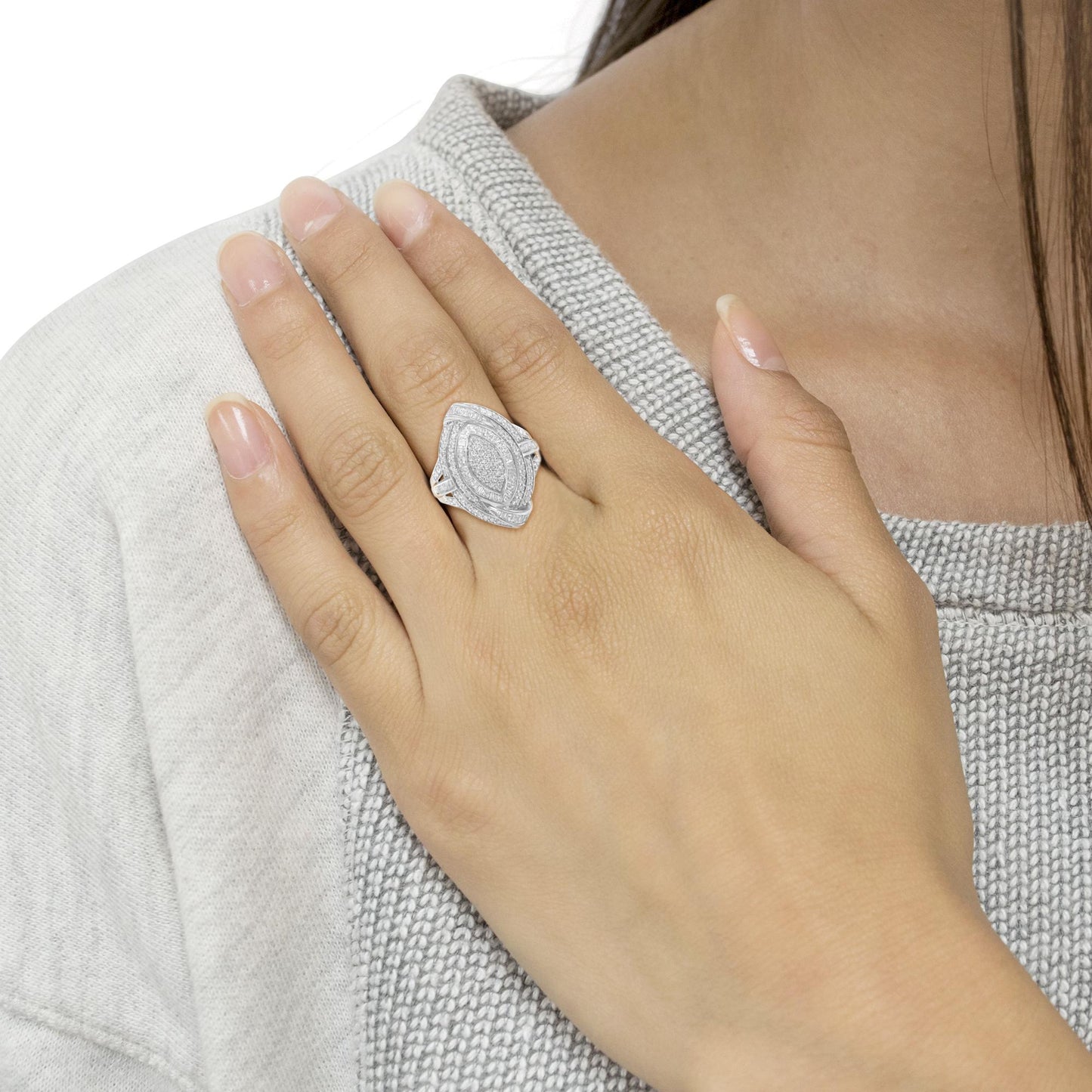 Close-up front angle of a white metal ring with round pave set white gemstones and baguette channel set white gemstones, worn on a model's hand.