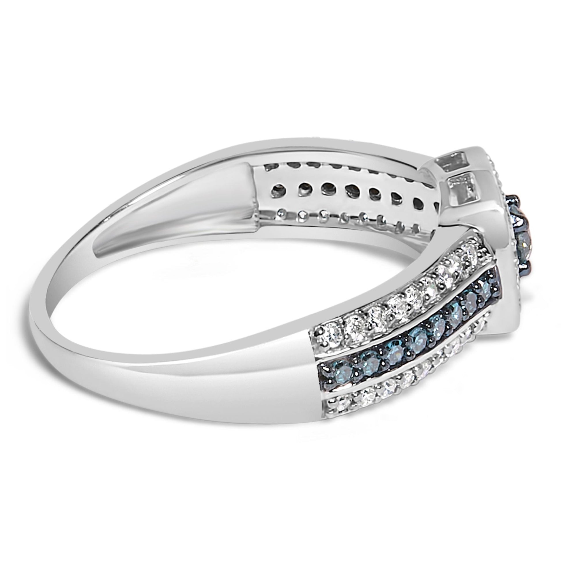 Side angle view of a white metal ring featuring prong-set round blue and white gemstones arranged in rows along the band and around the central setting.