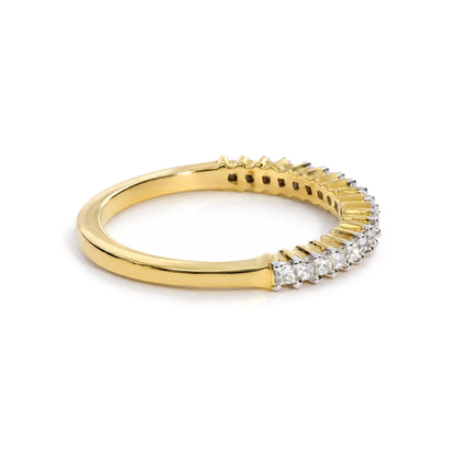 Close-up side angle of a yellow metal ring with a row of princess-shaped white gemstones in prong settings along the top half.