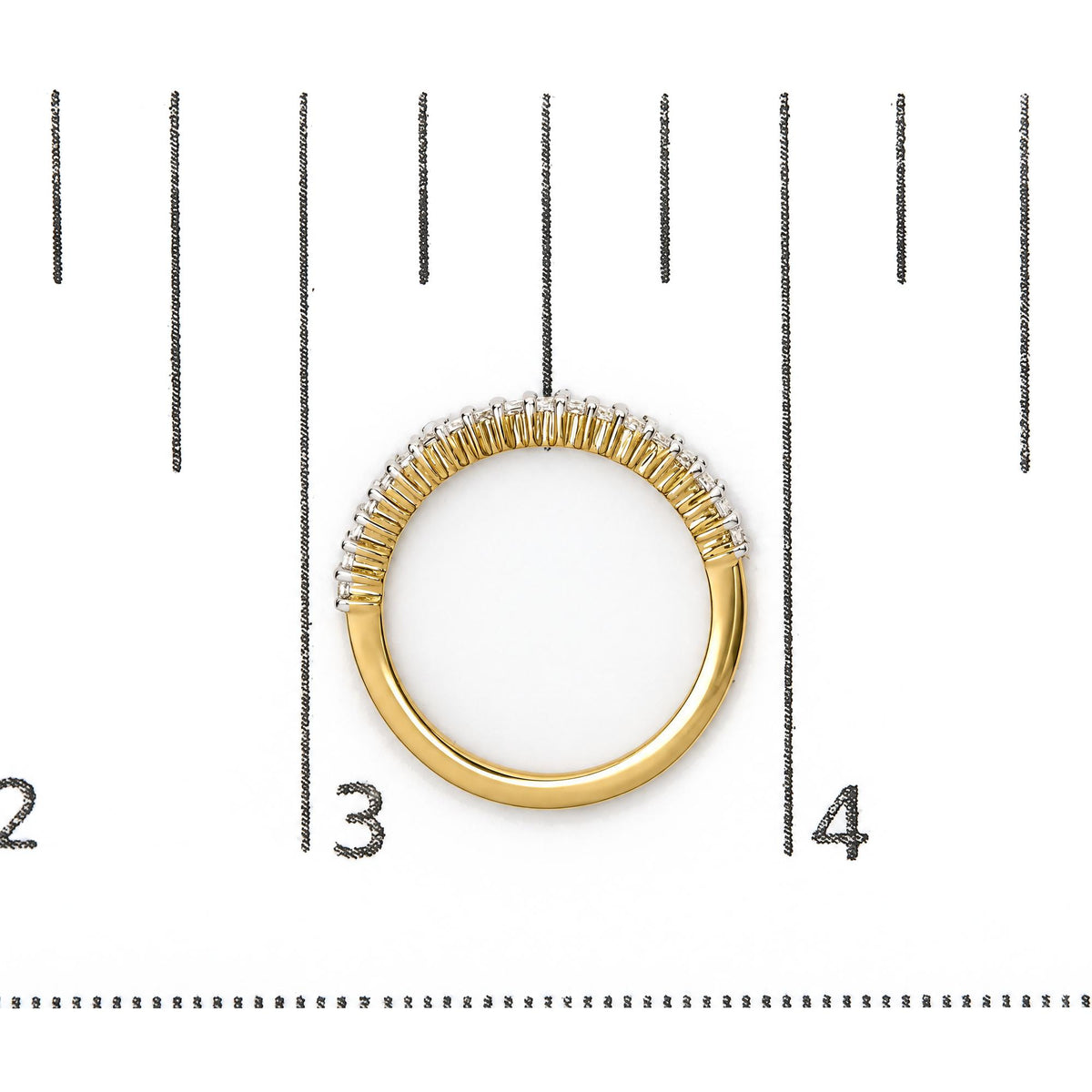 Close-up front angle of a yellow ring with white princess-shaped gemstones in prong settings, shown on a scale.