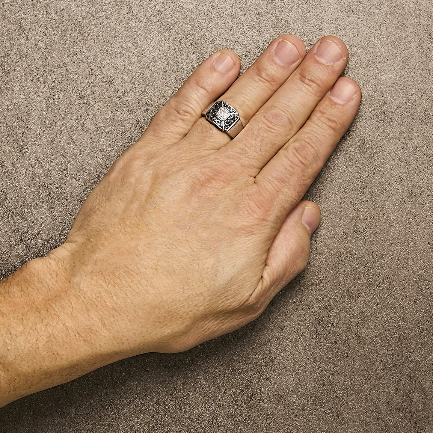 White metal ring with round black and white gemstones in pave setting, shown on a model's hand from a top angle.