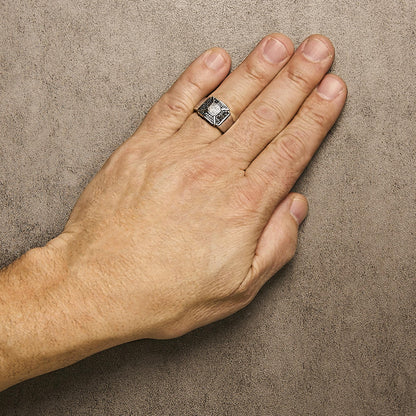 White metal ring with round black and white gemstones in pave setting, shown on a model's hand from a top angle.